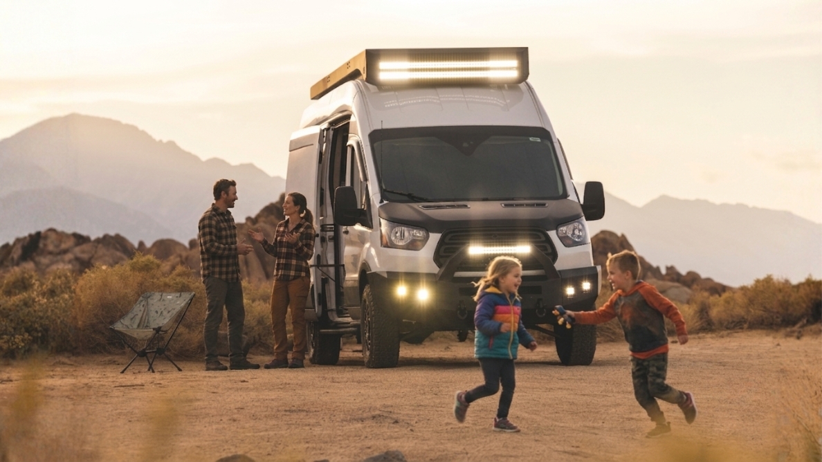 Enfants qui courent devant un van aménagé pendant que leurs parents parlent